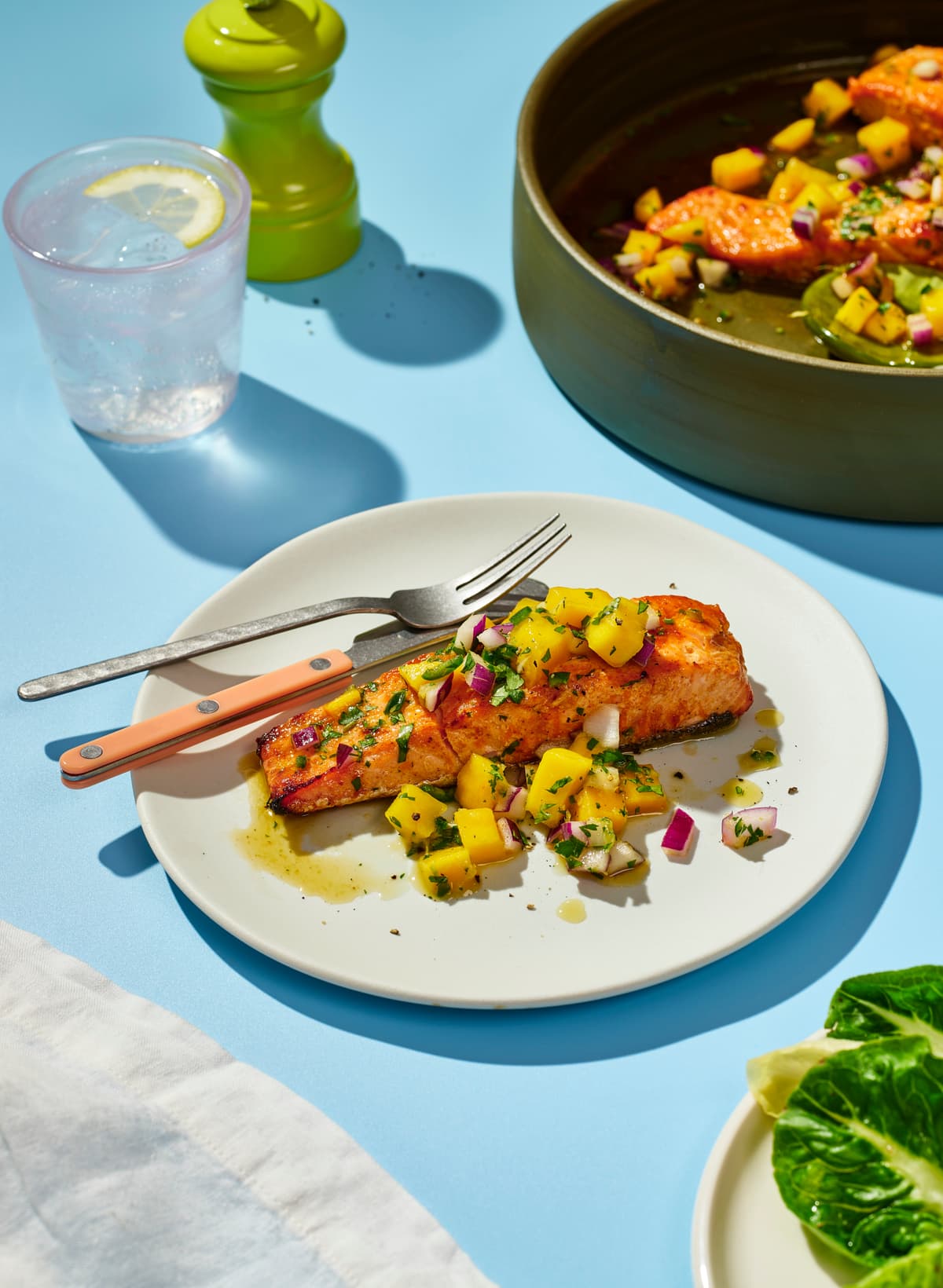 Plate with a piece of salmon covered in mango salsa on a dinner table